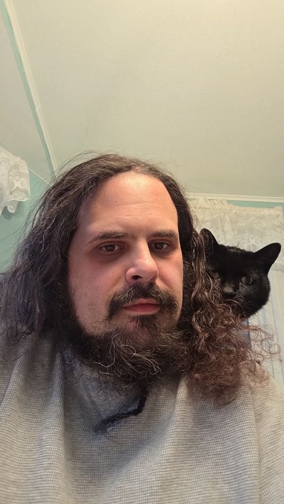 Selfie from the dining room with a black cat peeking over my shoulder at the camera.
