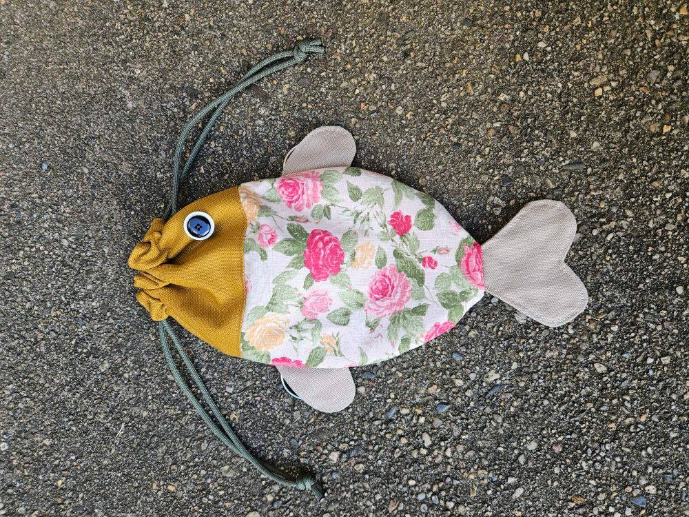 Foto von einer fischförmigen Tasche mit rosa geblümten Stoff als Körper, ockerfarbenem Kopf mit Knopfauge und beigefarbenen Flossen