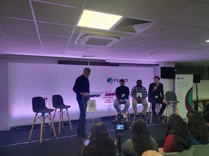 A photo of a panel of speakers sitting at stools at the conference 