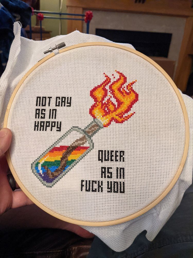 Embroidery of a rainbow colored molotov cocktail and text saying "Not gay as in happy, queer as in fuck you." 
