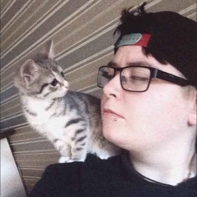 A photograph from 9 years ago of me and percival where he's a little kitten sitting in my shoulder and I'm on the right.