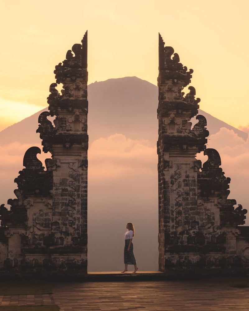 The real life reference of the Lempuyang temple in Bali. A large gate backlit by a golden sunset with a lone figure standing in the middle.