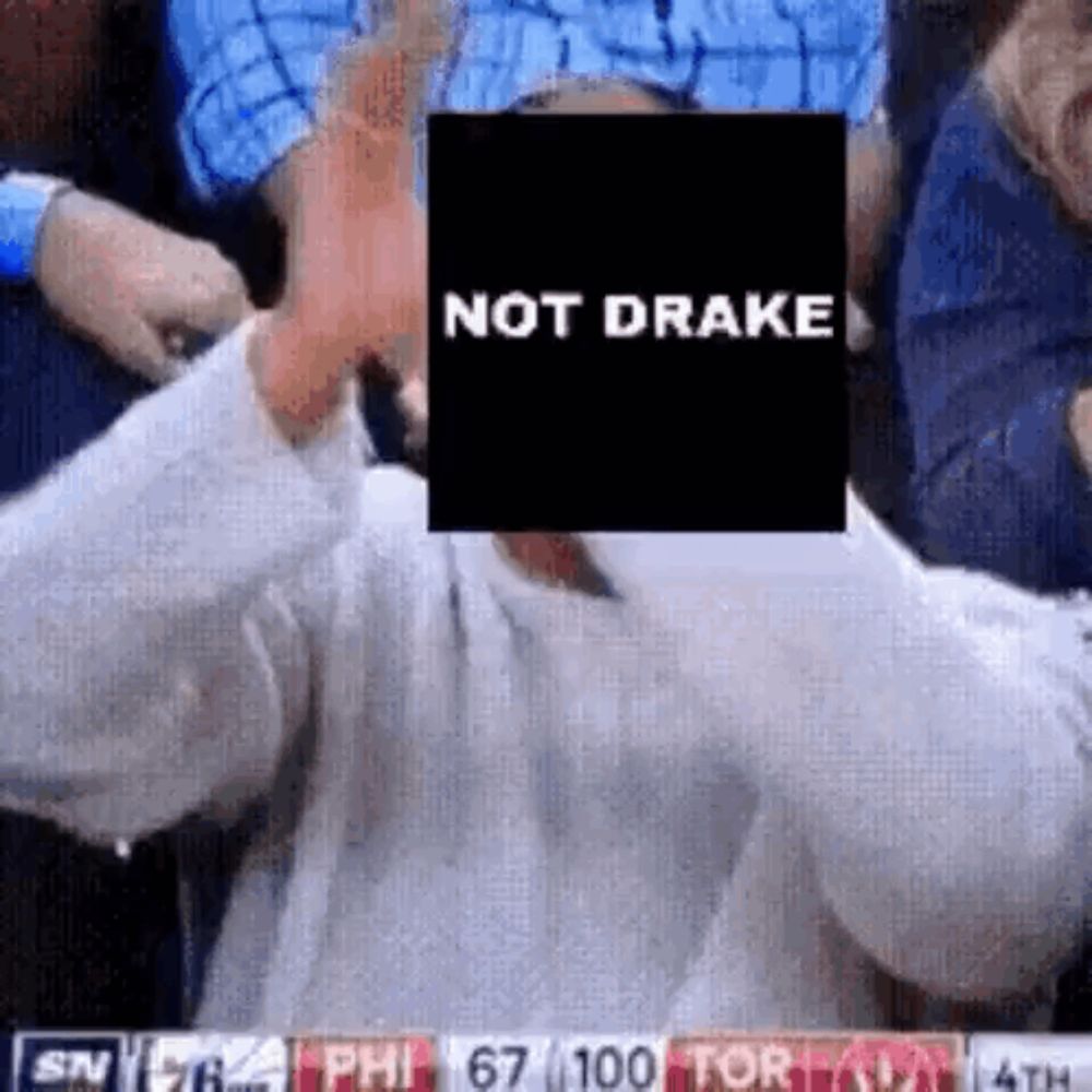 a man is sitting in a stadium holding a sign that says `` not drake '' in front of his face .