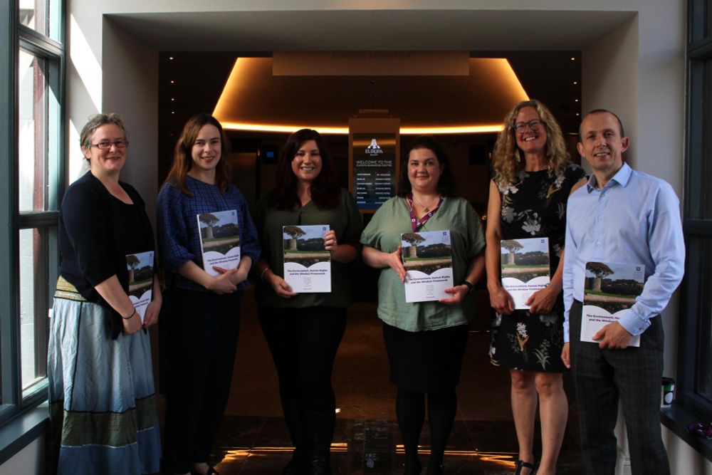 (From left to right) Photo of report author Dr Mary Dobbs, report author Dr Orla Kelleher, report author Dr Ciara Brennan, NIHRC Policy and Research Officer Dr Ivanka Antova, NIHRC Commissioner Helen Henderson and NIHRC Chief Executive Dr David Russell. Each of them are holding a copy of the NIHRC independent research report, 'The Environment, Human Rights and the Windsor Framework'.