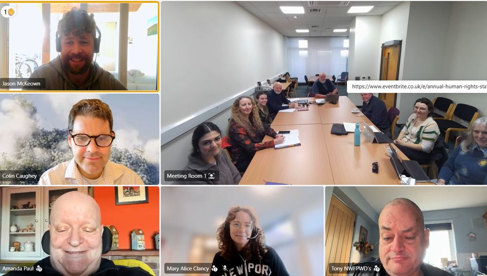 Picture showing a video call with multiple people on screens, one of which shows a room with several people around a table, with participants smiling at the camera. 