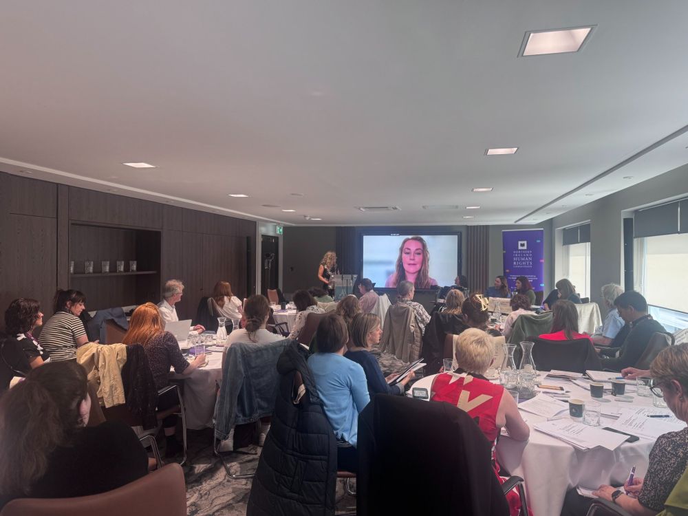 A photo of the event room, with Dr Lisa Claire Whitten on screen via Zoom responding to an audience question.