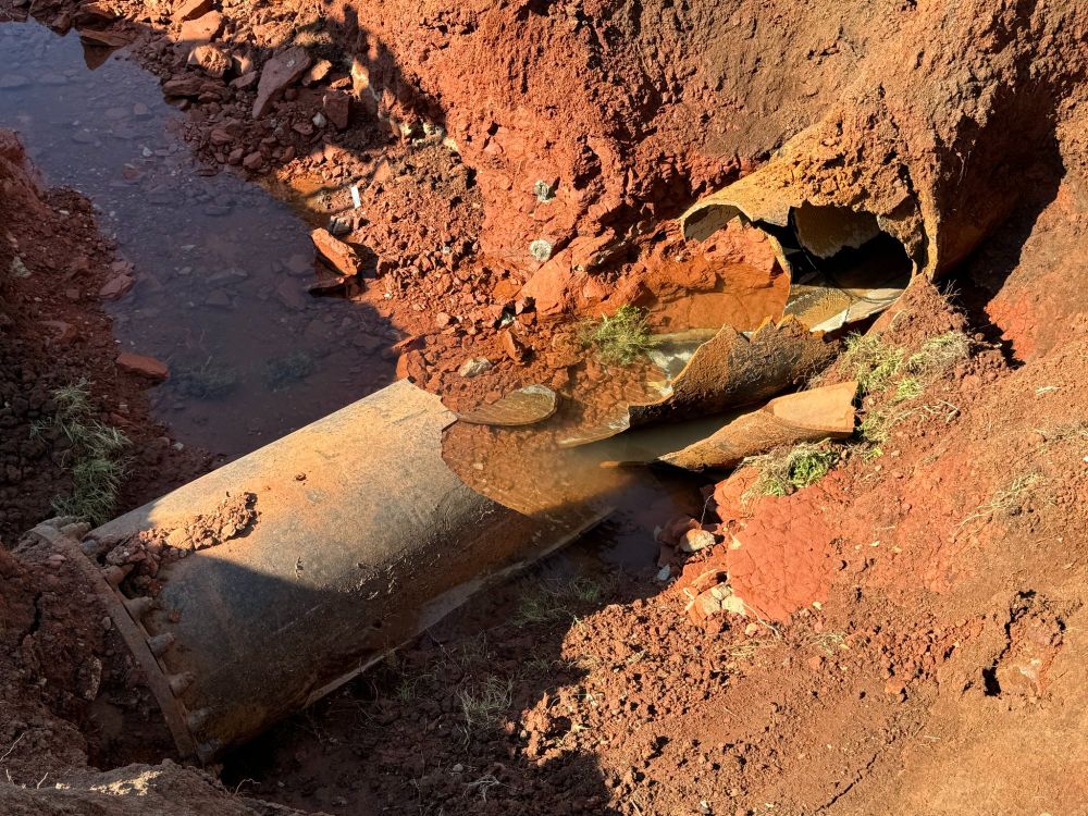 broken water main line in red dirt ditch