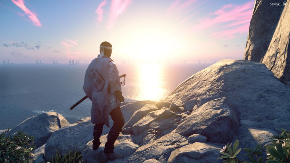 A man stands on a rocky out cropping and looks at a sunrise over the ocean