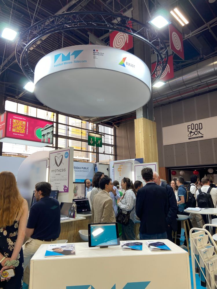 Des personnes discutant sur le stand IMT lors de VivaTech 2025. 