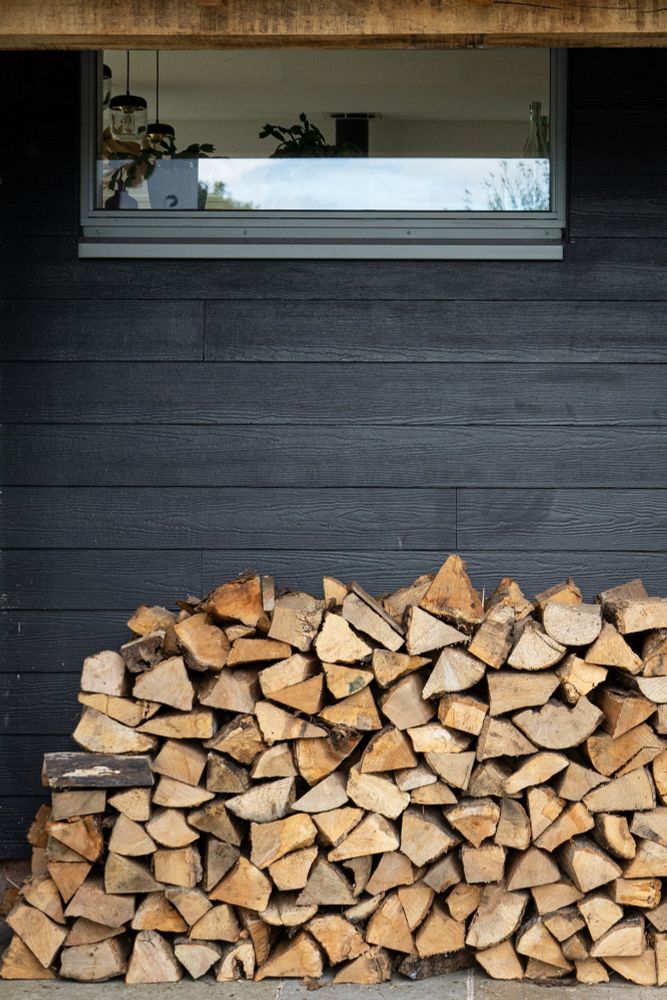Gris 2150 Window situated over a firewood pile in a black timber clad home
