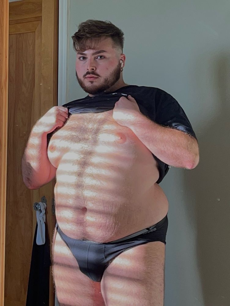 gorgeous cub lifts up shirt, revealing his plump belly and chest in the sunlight