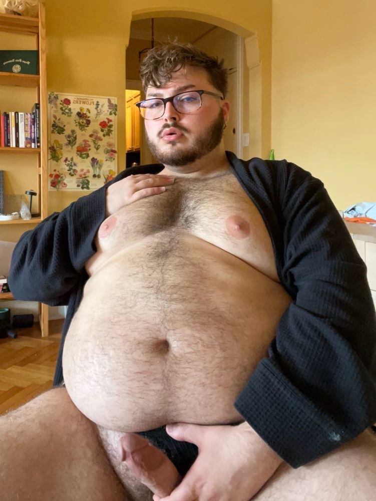 large plush sitting in black robe, holding his chest and his dick 