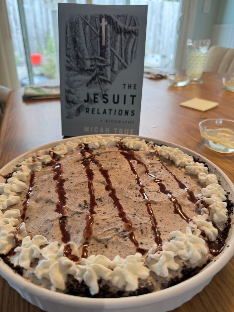 In the foreground, an ice cream pie. In the background, a book entitled The Jesuit Relations: A Biography.
