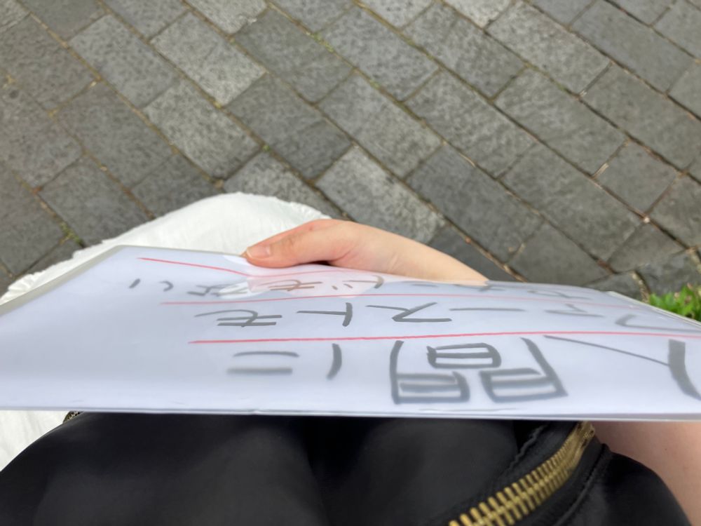 「人間にファーストもセカンドもない」と書かれた紙を屋外で持っている