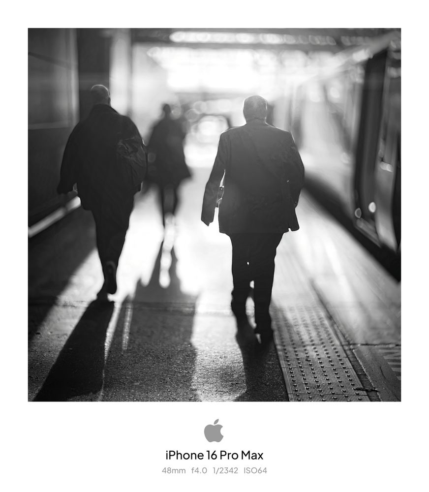 People in silhouette walking towards a low sun and getting on a train 