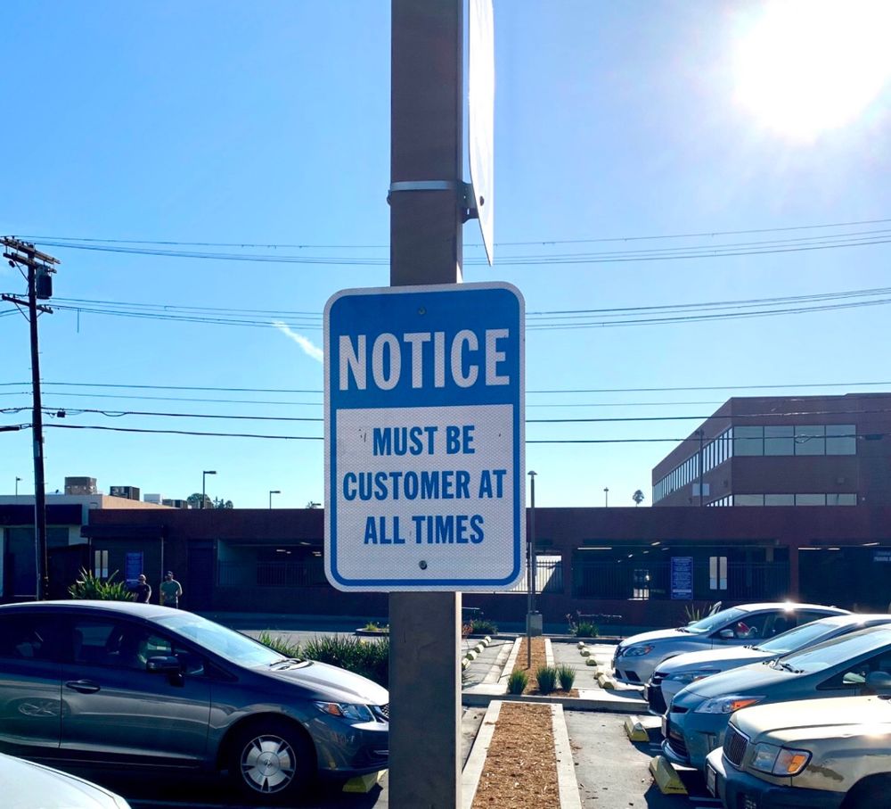 A sign in a parking lot reads: 
NOTICE
MUST BE CUSTOMER AT ALL TIMES