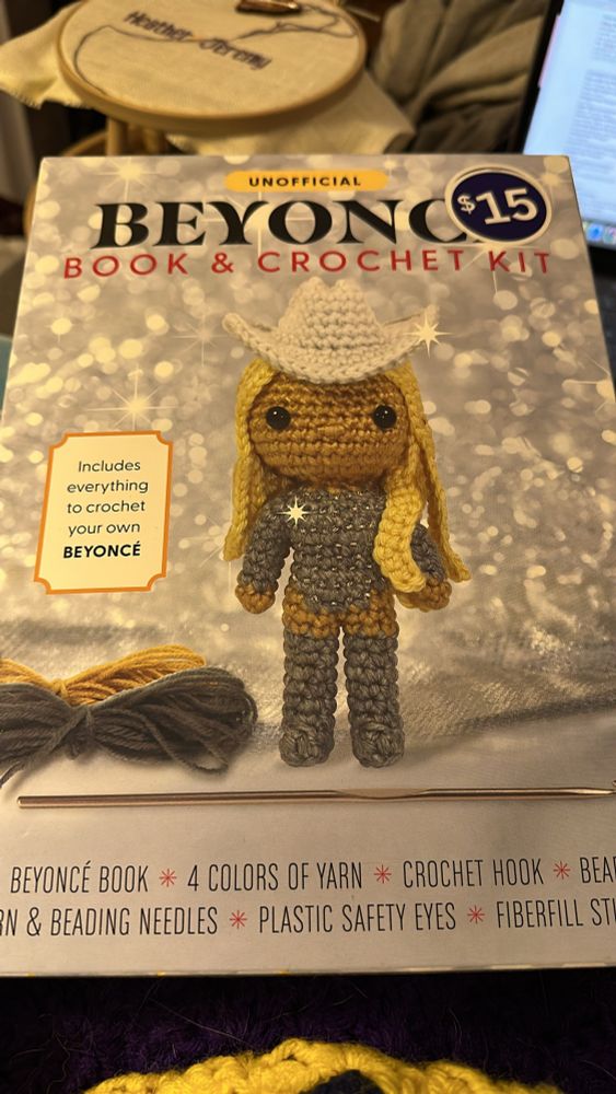 An unofficial Beyoncé cross stitch kit of Beyoncé wearing a silver long sleeve body suit, silver boots, and a white cowboy hat 