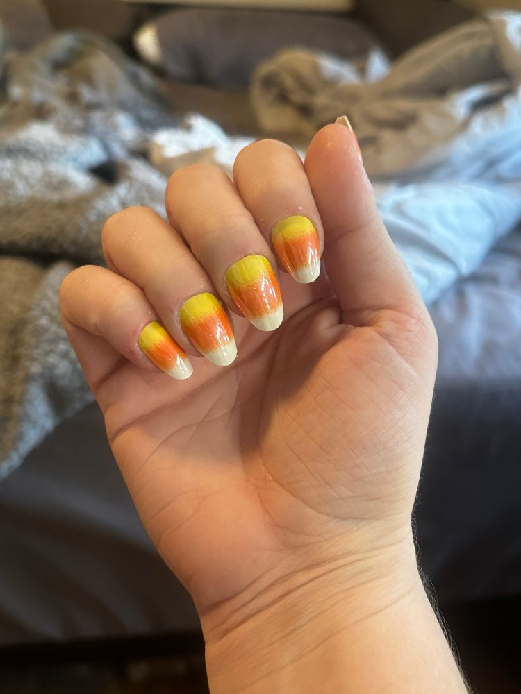 my hand with fake nails shaped like candy corns 