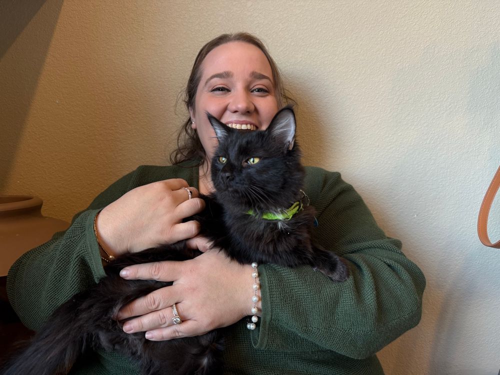 Brandey holding a young black kitten in her arms