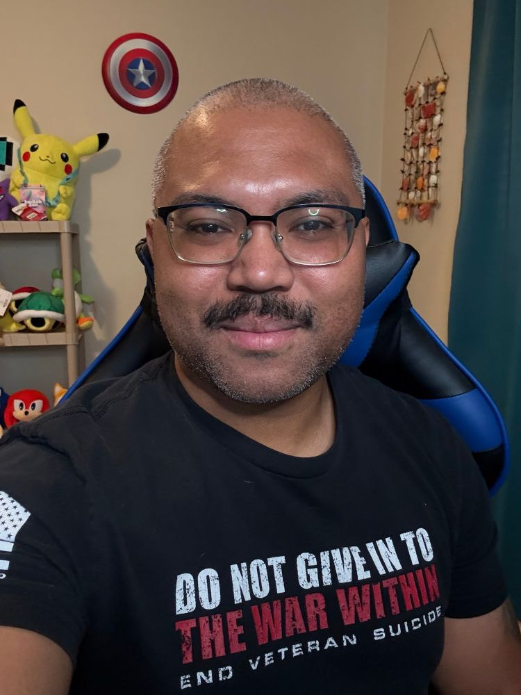 A selfie of Jay with a relaxed smiled. He is wearing a black shirt that says “Do Not Give In To The War Within End Veteran Suicide”