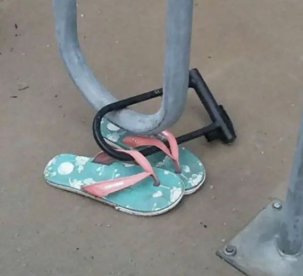 A pair of flip flops locked to a bicycle stand. 