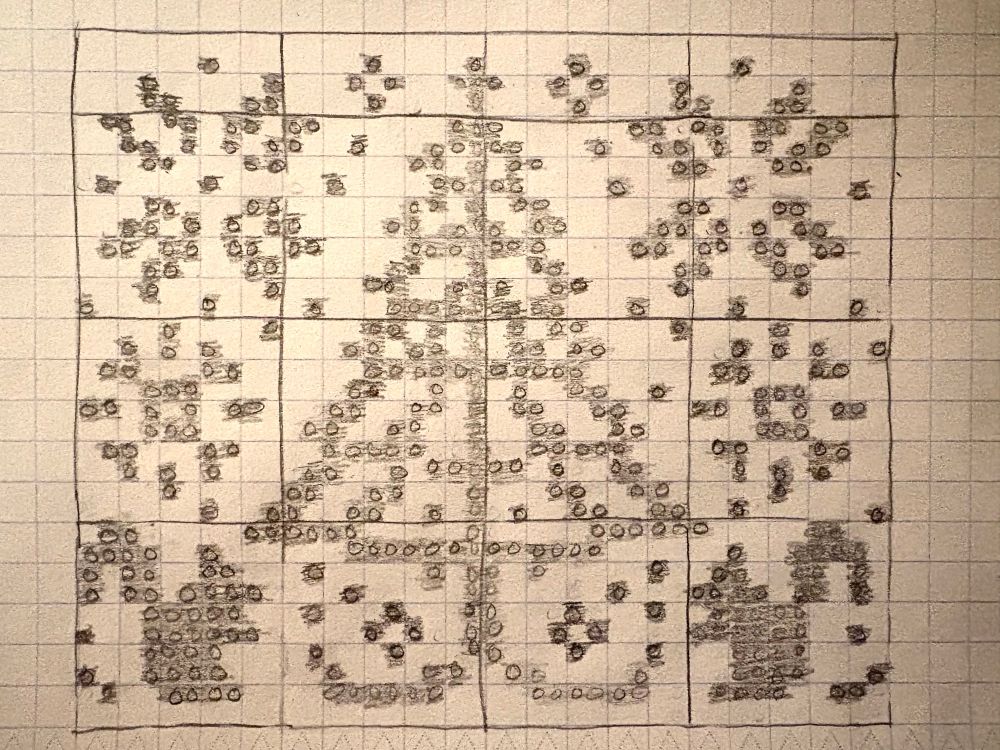 Graph paper chart pattern written in pencil. The pattern centers a pine tree with two squirrels beneath it and snowflakes in the sky around the tree. 