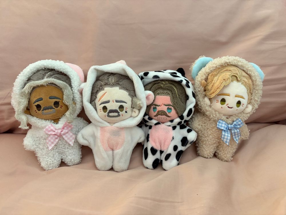 Four 10cm OFMD dolls by Rights. Left to right, Ed in a white car onesie, Izzy is a unicorn onesie, Jack in a cow onesie, and Stede in a teddy bear onesie. They are on pink sheets. These are the outfits they wear all the time. They’re really cute. 