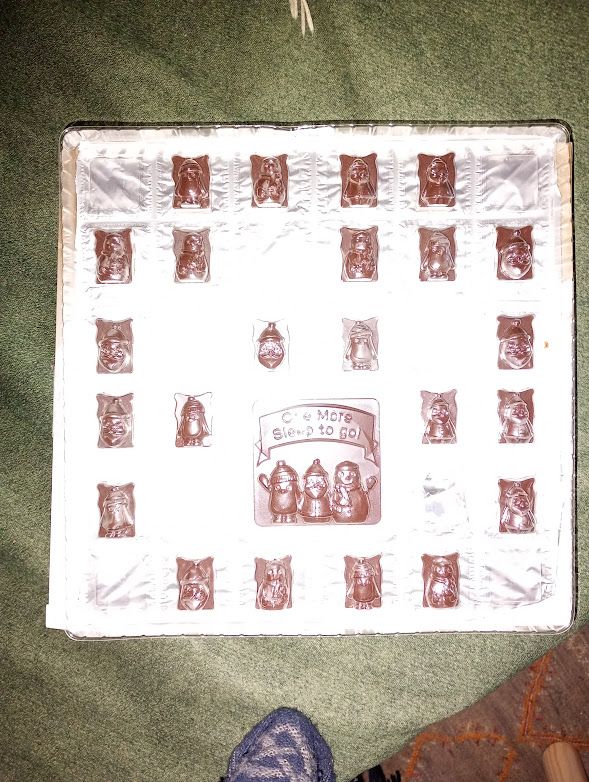 A silvery tray of chocolates with the foil behind and the chocolate and clear plastic in front. There are plenty of gaps in between the chocolates but 24 chocolates in all.