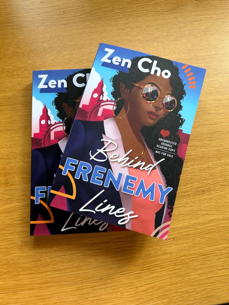Two Advance Reading Copies of BEHIND FRENEMY LINES by Zen Cho, with a cover featuring a brown-skinned woman with curly hair against the London skyline