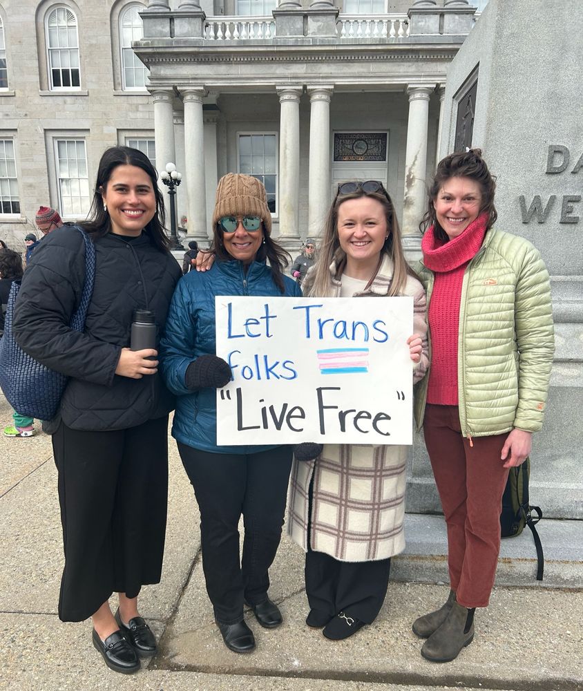 Myself, my colleague from Repro Equity Now, and Equality Health Center staff in front of the NH State House with a sign saying “Let Trans Folks ‘ Live Free ‘ “