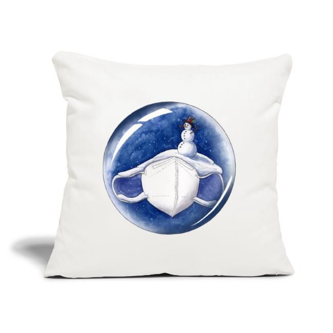 Ein helles Kissen mit Schneekugelmotiv. Auf einer schneebedeckten Maske sitzt ein kleiner Schneemann und blickt in die stille Winternacht.