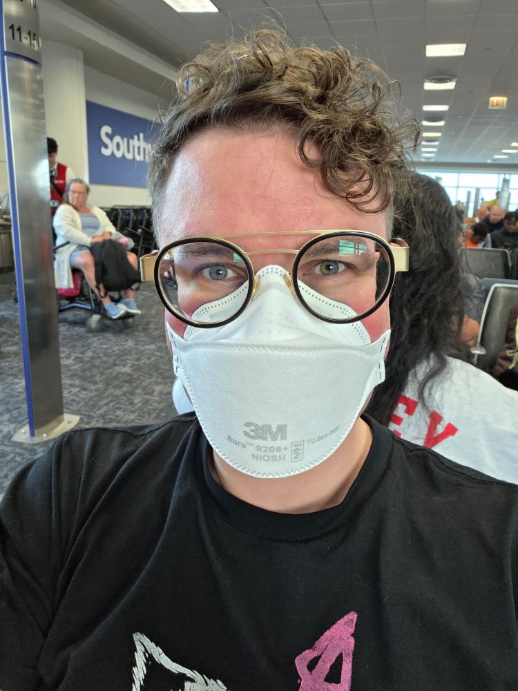 An extremely tired 35 year old man with curly hair and an N95 mask. He has clearly spent the last week desperately preparing for two major conventions in a row.

Despite all that he is hot. Probably one of the hottest people you have ever seen. It's not even a sexual thing. He is hot in a way that makes you respect him. 