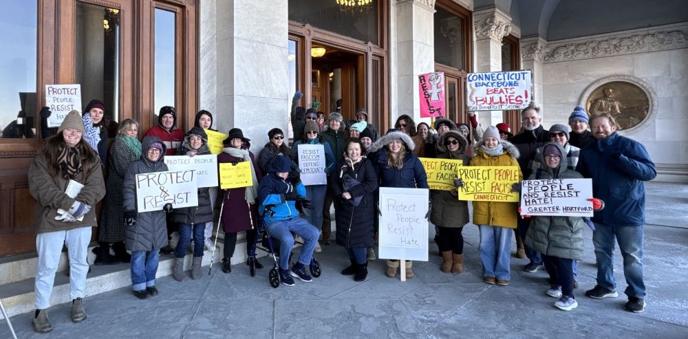 Group picture from the CT State Capitol at the SURJ Day of Action rally in Hartford. There are about 30 people, many holding signs including messages such as "Protect People Resist Hate!" and "Protect and Resist"