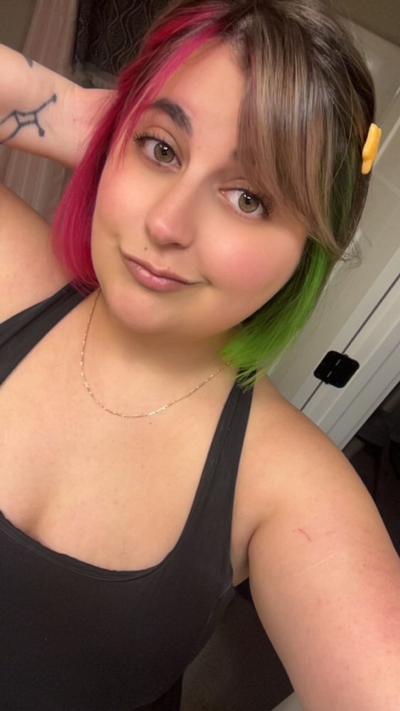 selfie with 5+ in. of hair cut off into a bob with neon green/pink face framing accent pieces on opposite sides 