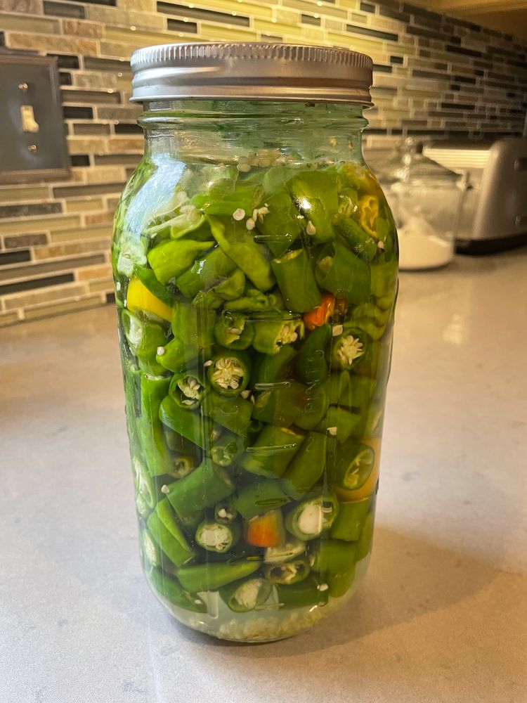 A two quart jar of chopped chili peppers in a salt brine