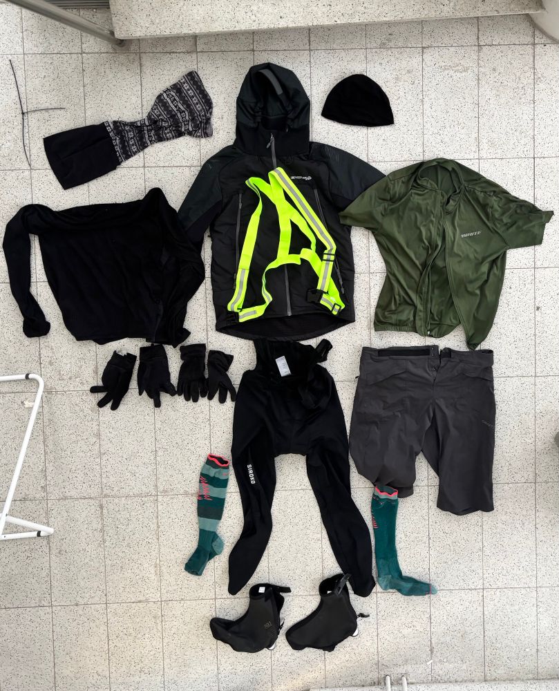 läjä pyöräilyvaatteita levitettynä maahan esittelemään kokonais varustusta