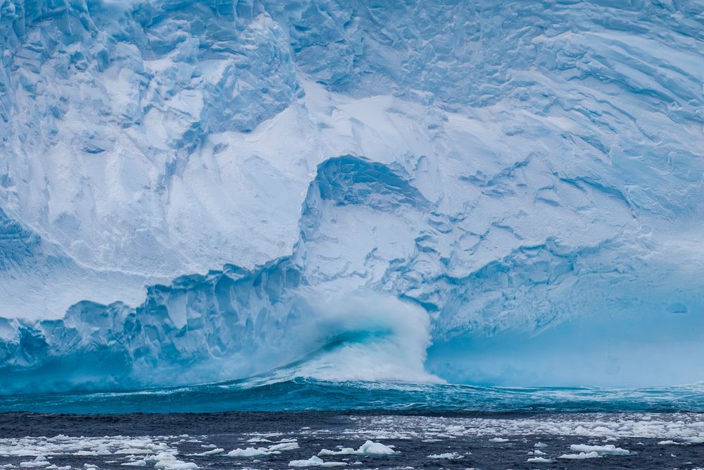A wave crashing into an Antarctic ice shelf. These waves damage the ice shelf causing more icebergs to break off.