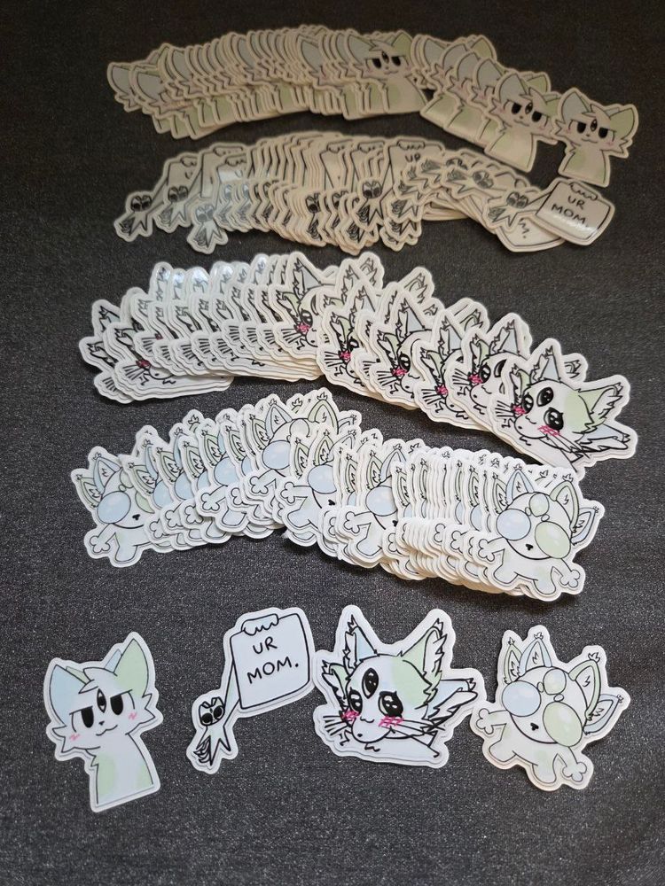 A photo of a bunch of stickers showing a light green, blue, and white critter