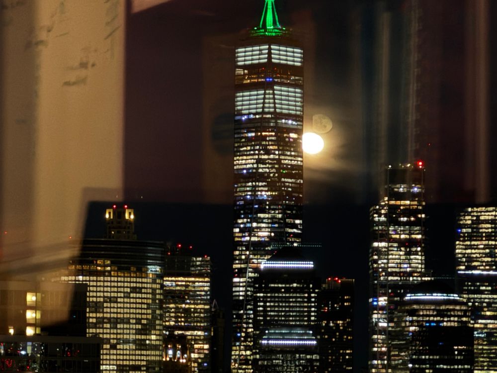 The moon shining brightly behind the World Trade Center.