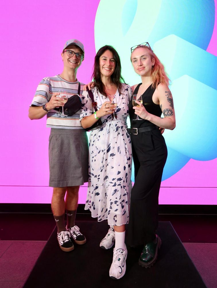 Three people raise their glasses towards the camera
