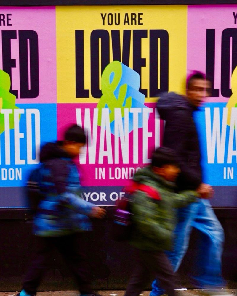 A man and two boys walk past Loved & Wanted posters