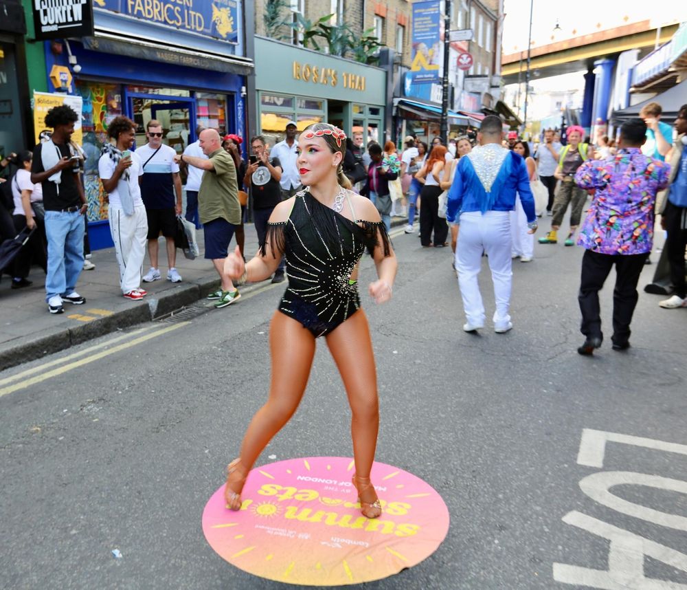 A woman in a leotard dances on the 'Summer Streets' sign on the road