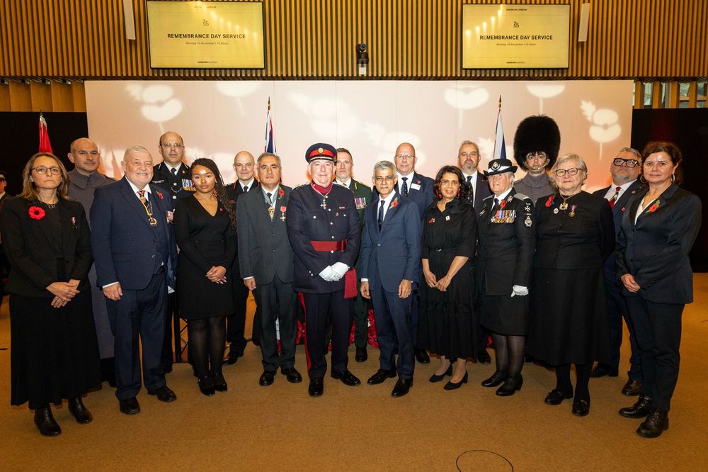 The Mayor of London standing with veterans, uniformed officers, and guests for a group photo following the Remembrance Day service at City Hall.