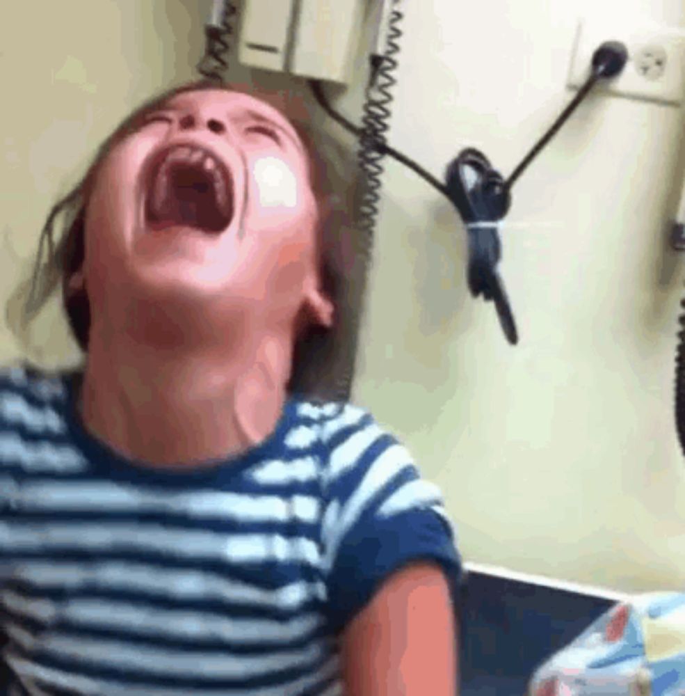 a young boy is laughing with his mouth open in a striped shirt .