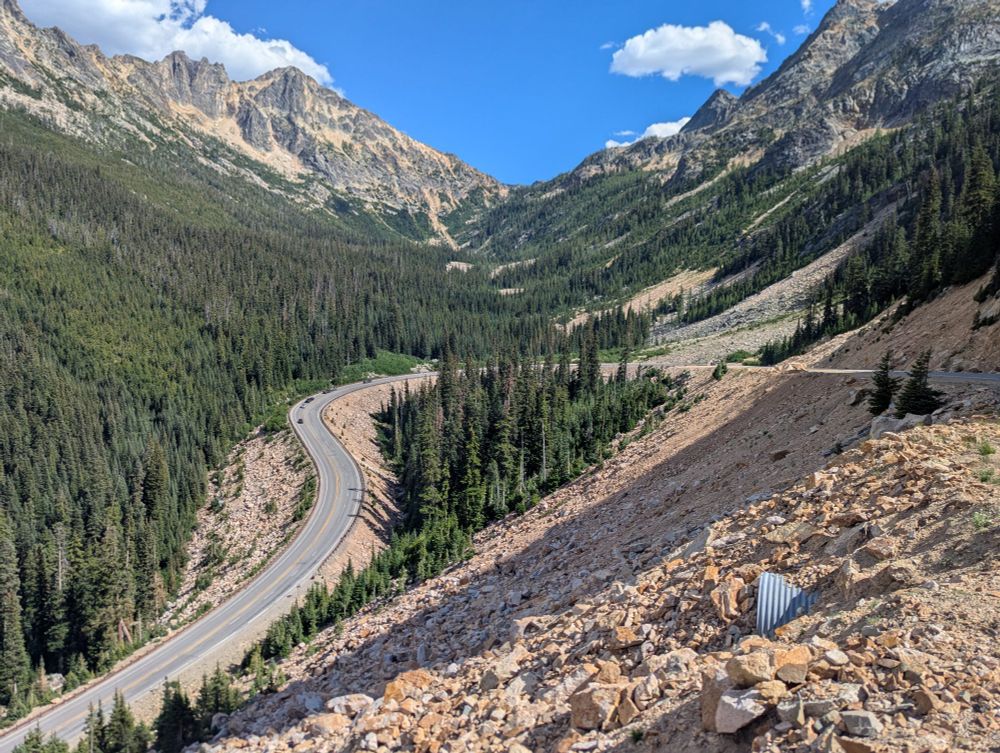 A road making a hairpin turn in Washington Pass nestled between trees and rocks