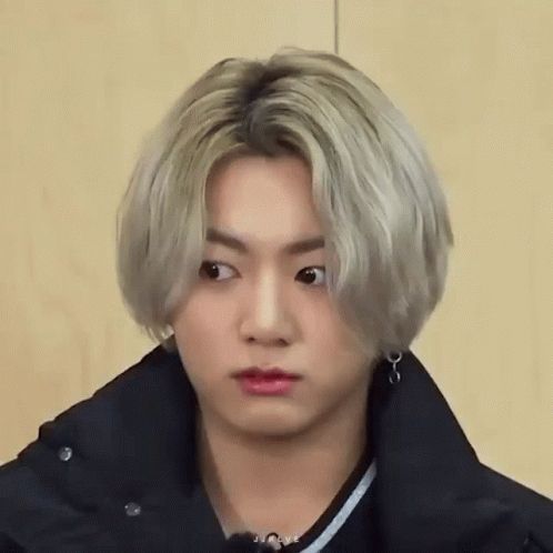 Jung Kook of BTS with longish blonde hair staring and pondering his hyungs’
 feedback answers on Run BTS while he begins to question authority 