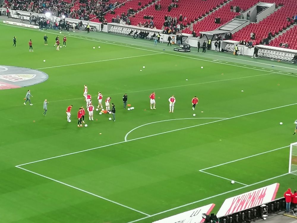 Blick auf den Rasen des Neckarstadions. Spieler wärmen sich auf. 