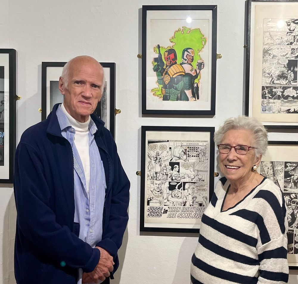 Photograph of Steve Dillon’s parents next to framed Judge Dredd artwork 