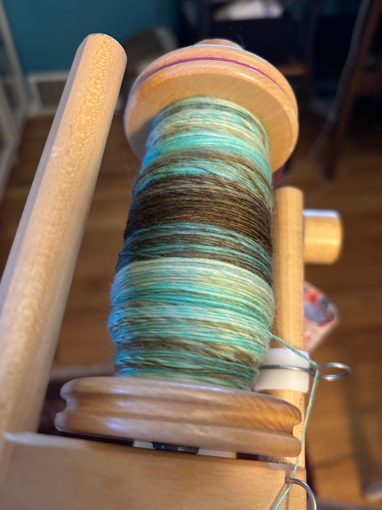 A handspun single yarn in tones of brown, green, aqua and white