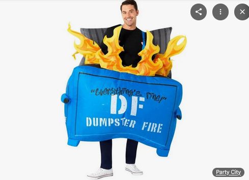 A smiling man wears an inflatable dumpster fire costume. It's blue. And yes appears to be on fire. Text on the front says "everything's fine!" DF dumpster fire